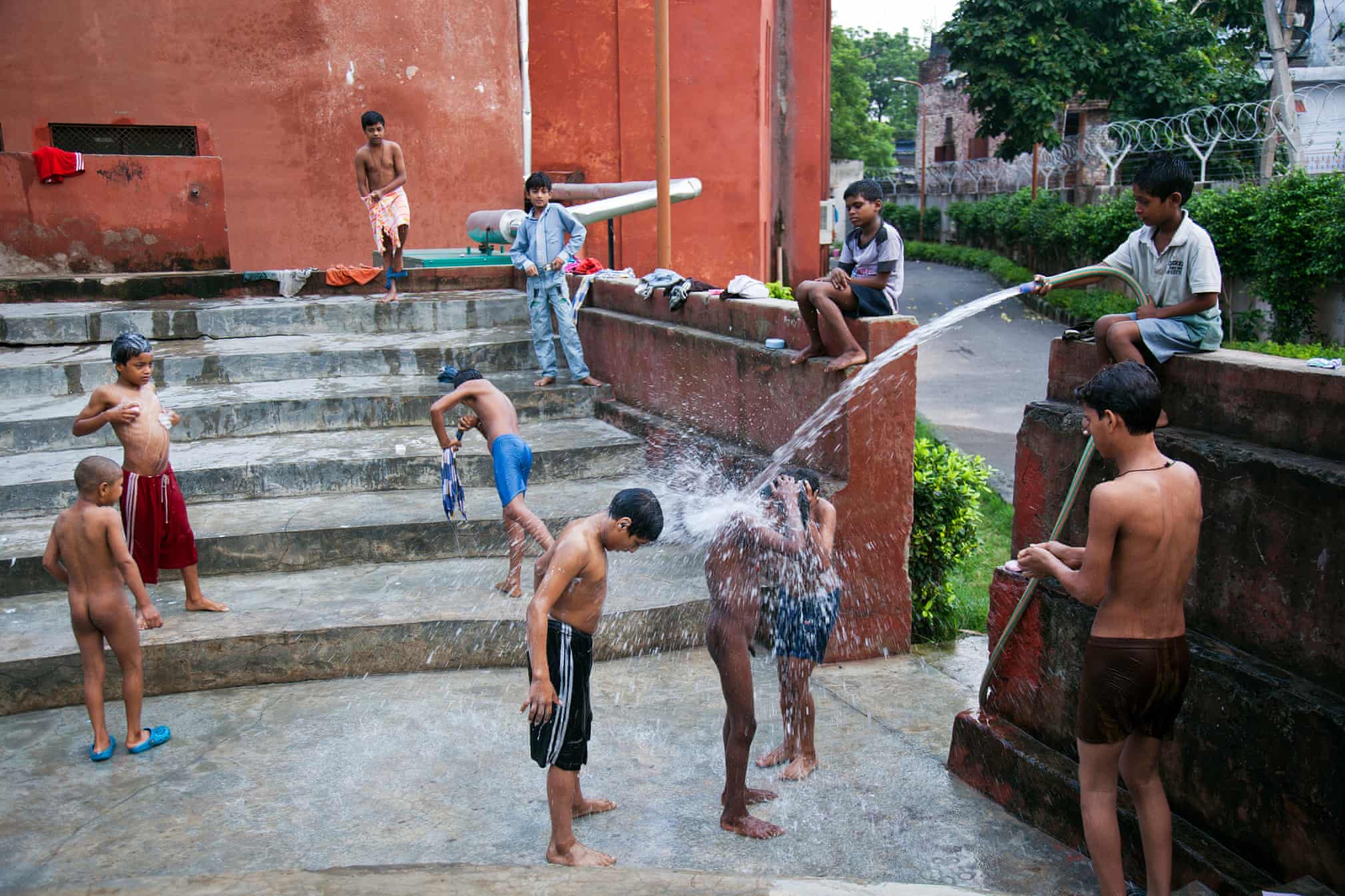 Мальчики принимают душ во дворе приюта.