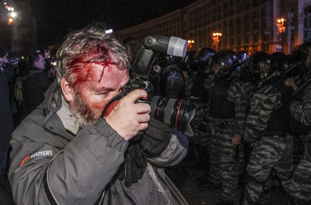 Раненый фотограф агентства Reuters Глеб Гаранич, который был ранен сотрудниками ОМОНа, фотографирует демонстрантов ОМОНа во время драки на демонстрации в поддержку интеграции в ЕС на площади Независимости в Киеве 30 ноября 2013. Фото из архива 2013 года предоставлено Reuters.
